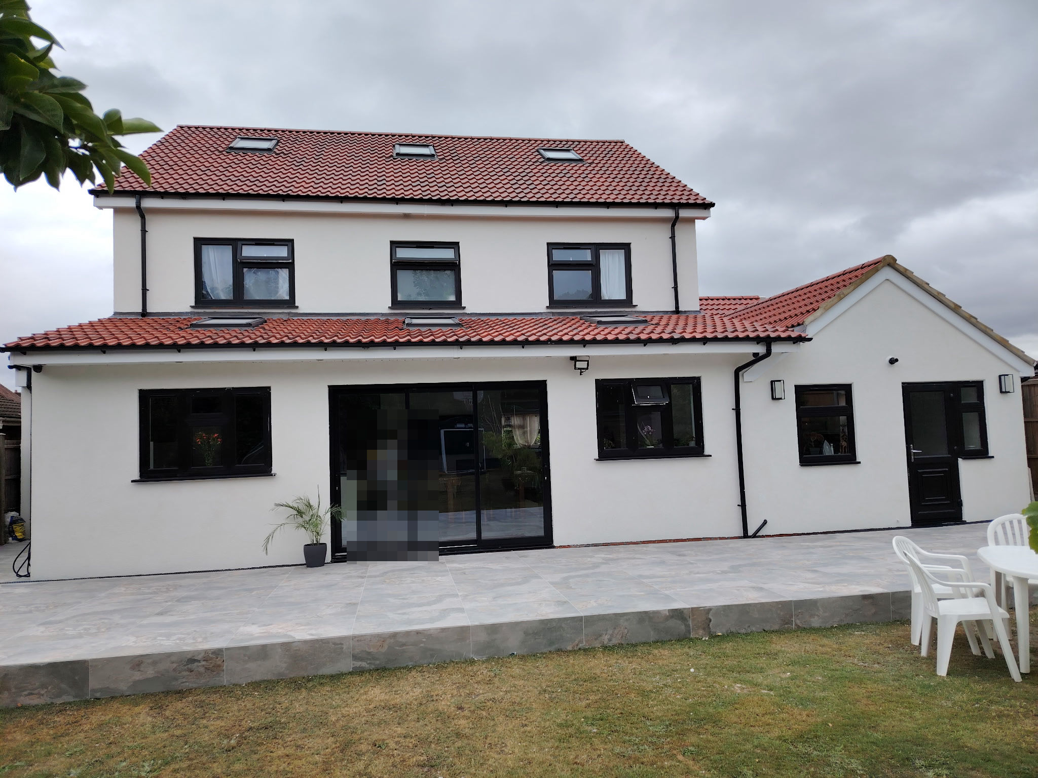 The completed home from the rear, with full-width glazing and a new patio
